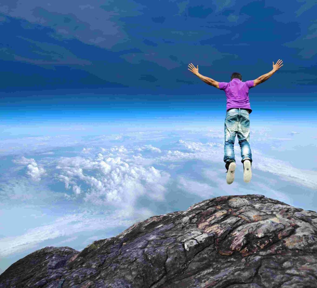 Man jumping from a cliff with arms spread, feeling free and liberated